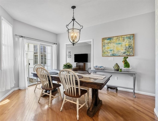 dining room featuring light wood-style floors, baseboards, and an inviting chandelier