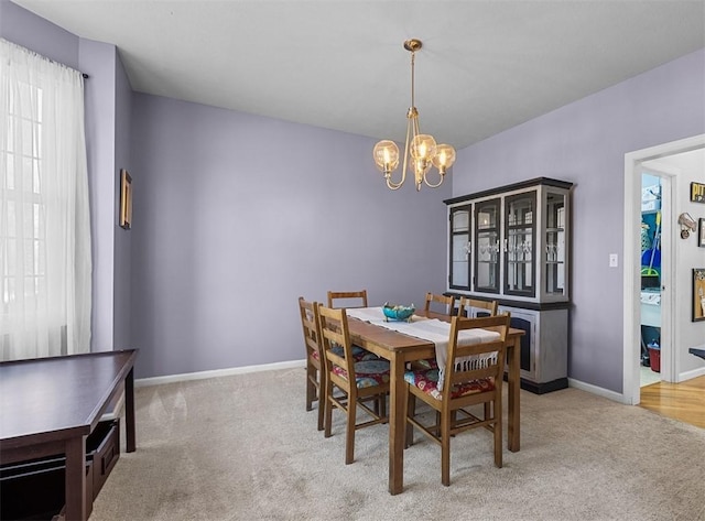 dining room with an inviting chandelier, baseboards, and light carpet