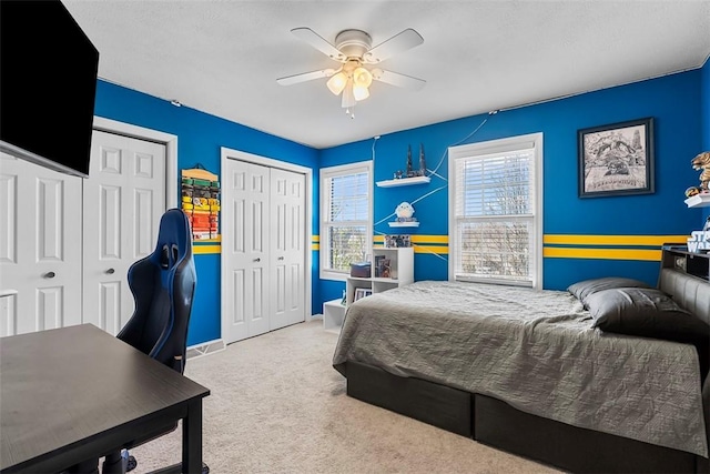 bedroom featuring two closets, a ceiling fan, carpet flooring, and baseboards
