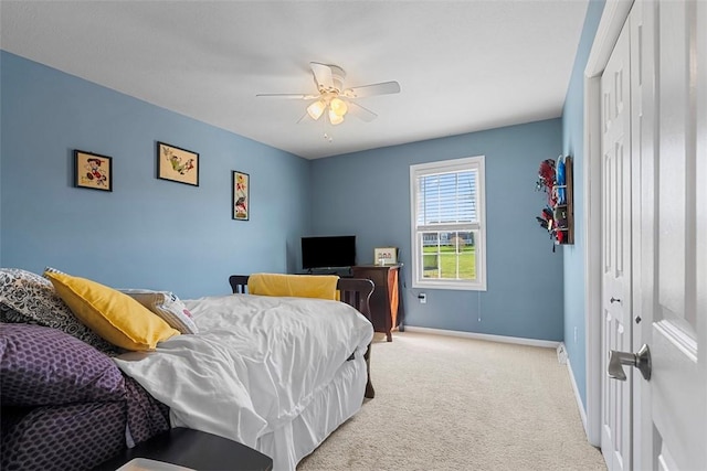 bedroom with baseboards, ceiling fan, light carpet, and a closet
