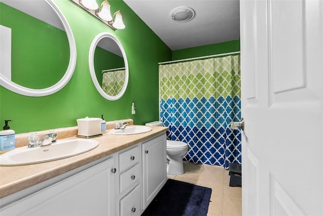 bathroom with double vanity, a sink, tile patterned floors, and toilet