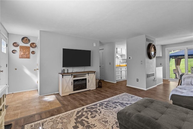 living area with baseboards, dark wood-type flooring, and visible vents