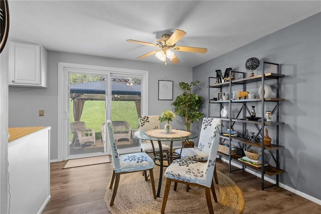 dining space with a ceiling fan, baseboards, and wood finished floors
