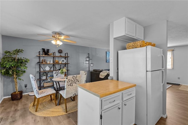 kitchen with freestanding refrigerator, light countertops, white cabinetry, a ceiling fan, and light wood-style flooring
