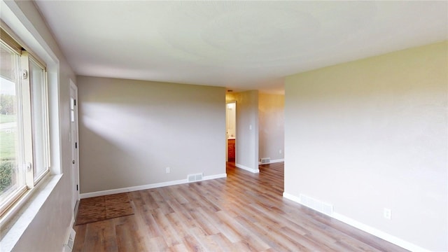spare room with visible vents, light wood finished floors, and a wealth of natural light
