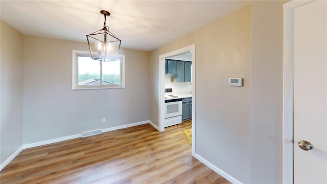 unfurnished dining area featuring baseboards, visible vents, an inviting chandelier, and light wood finished floors