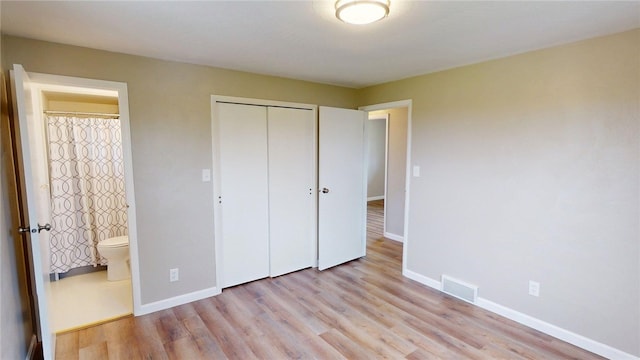 unfurnished bedroom featuring visible vents, a closet, light wood-style floors, ensuite bathroom, and baseboards