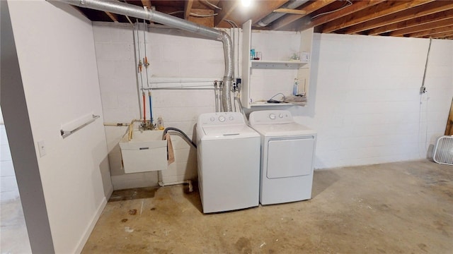 washroom with laundry area, washer and clothes dryer, a sink, and concrete block wall