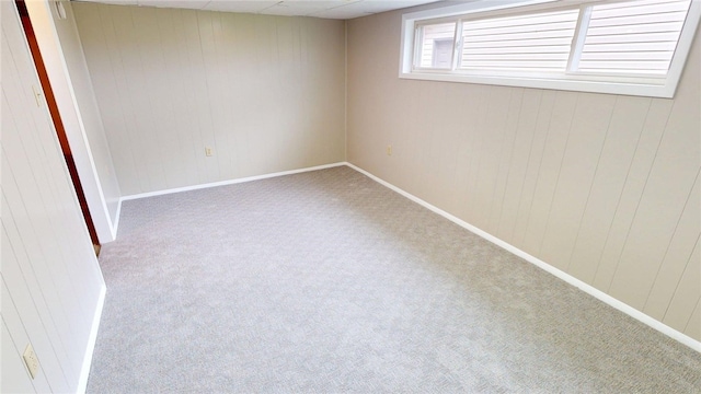 carpeted empty room featuring wooden walls and baseboards