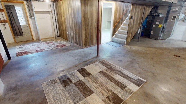 basement with heating unit, stairs, and wooden walls