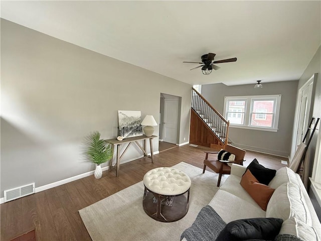 living area with stairs, a ceiling fan, baseboards, wood finished floors, and visible vents