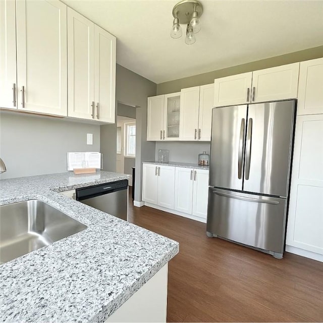kitchen with dark wood-style flooring, appliances with stainless steel finishes, a sink, white cabinets, and glass insert cabinets