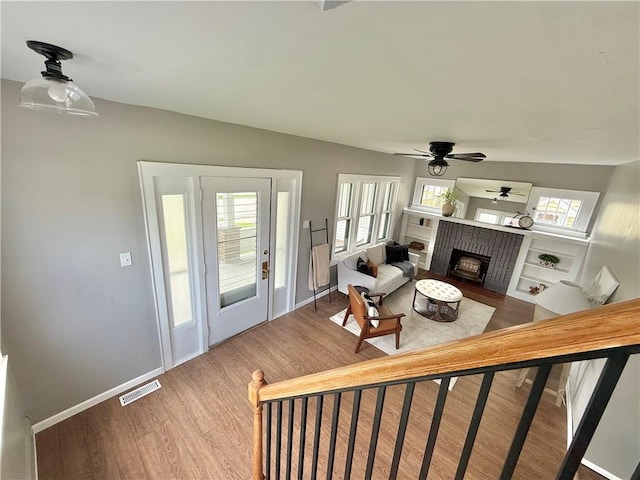 living room featuring ceiling fan, visible vents, wood finished floors, and a wealth of natural light