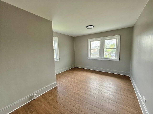 spare room with baseboards and wood-type flooring