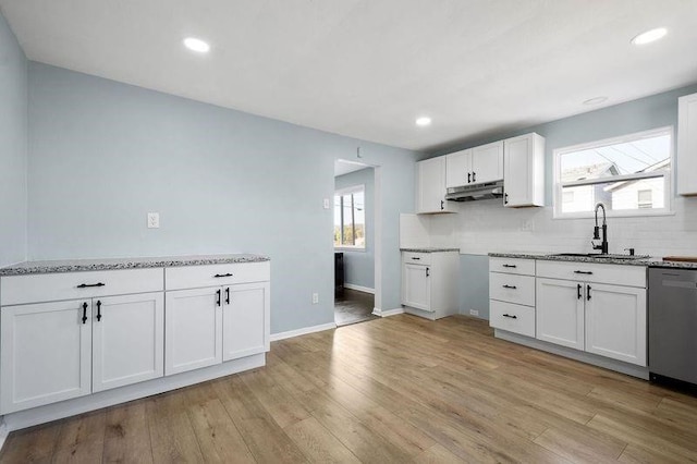 901 Union Ave, Mckeesport, PA 15132 - kitchen featuring dishwasher, under cabinet range hood, white cabinets, a sink, and backsplash