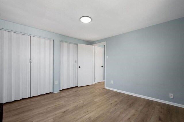 901 Union Ave, Mckeesport, PA 15132 - unfurnished bedroom featuring baseboards, wood finished floors, and two closets