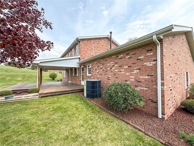 rear view of property featuring a wooden deck, central AC unit, a yard, and brick siding