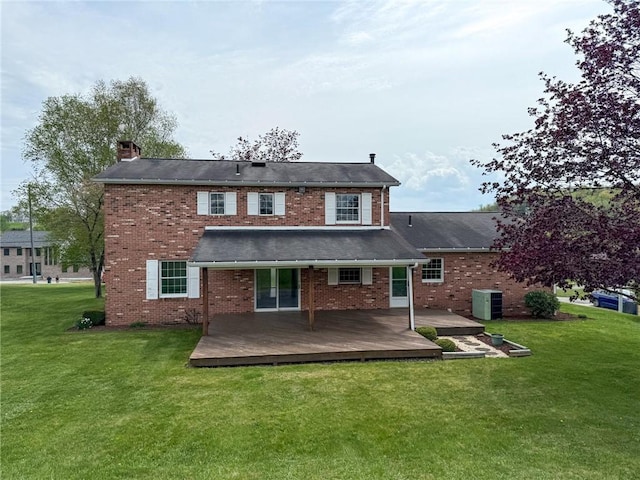rear view of property featuring a lawn, a chimney, a deck, and brick siding