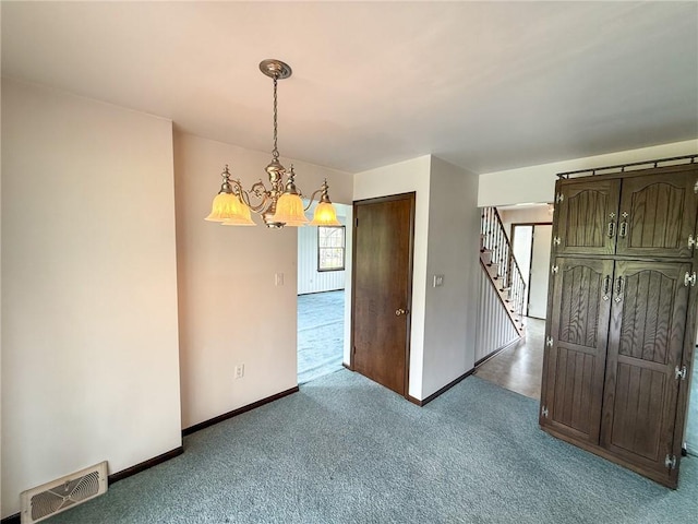 carpeted spare room with a notable chandelier, visible vents, baseboards, and stairway