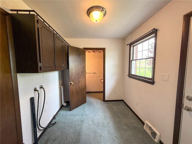 laundry area with cabinet space, light colored carpet, radiator, baseboards, and visible vents