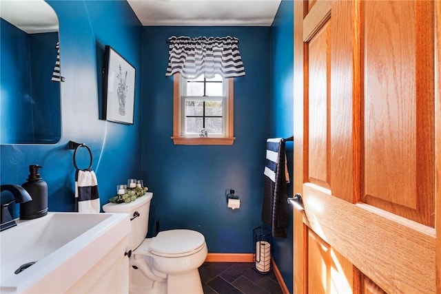bathroom with toilet, baseboards, a sink, and tile patterned flooring