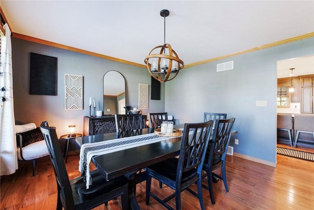 dining area featuring visible vents, crown molding, wood finished floors, baseboards, and a notable chandelier