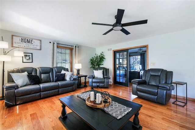 living room featuring visible vents, light wood finished floors, ceiling fan, and baseboards