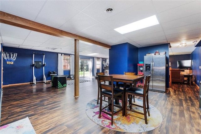 dining space featuring baseboards, a paneled ceiling, and wood finished floors