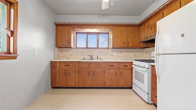kitchen with white appliances, under cabinet range hood, decorative backsplash, and a sink