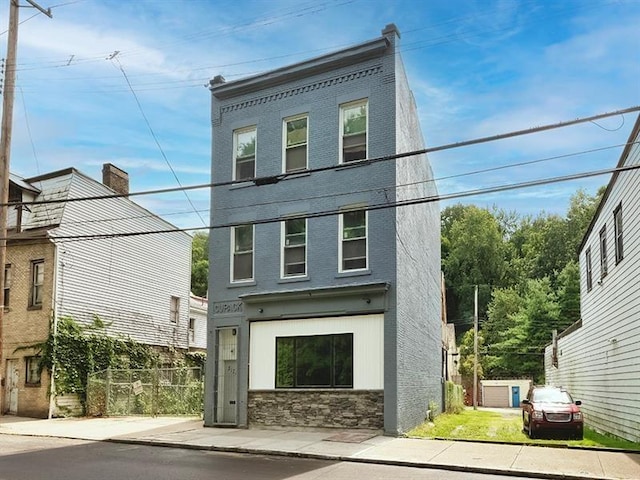 view of front of house with brick siding, fence, and stone siding