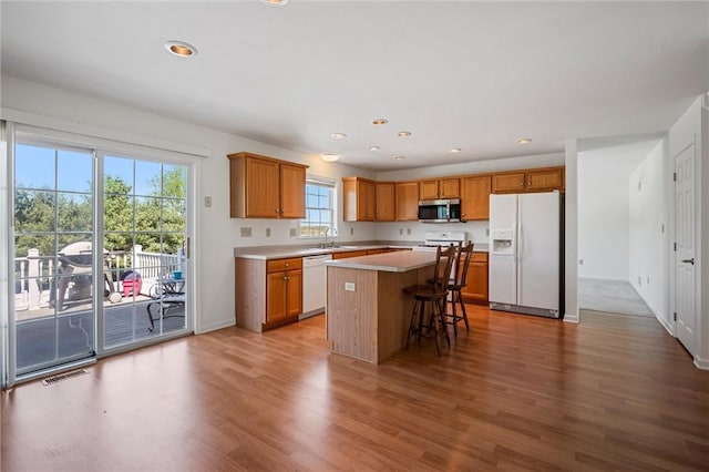 kitchen featuring a kitchen island, white appliances, wood finished floors, and visible vents