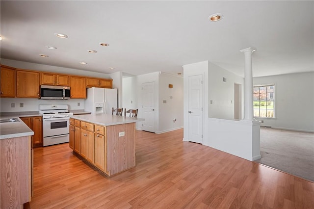 kitchen with light countertops, ornate columns, a kitchen island, and white appliances
