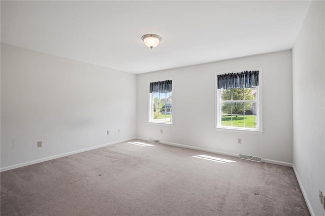 spare room with carpet flooring, baseboards, and visible vents