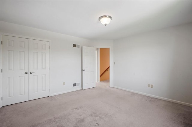 unfurnished bedroom with baseboards, carpet, a closet, and visible vents