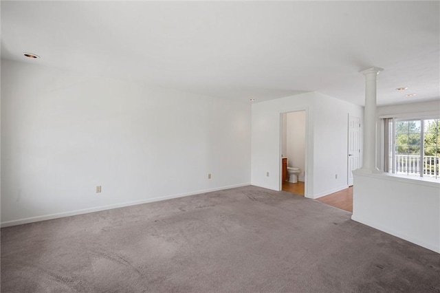 empty room featuring baseboards, carpet, and decorative columns