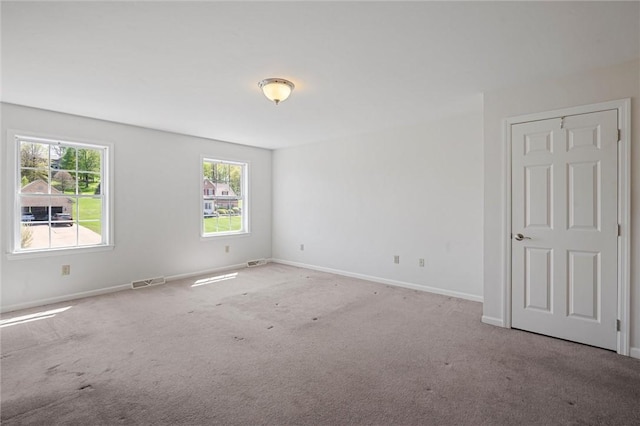 empty room with carpet flooring, baseboards, and visible vents