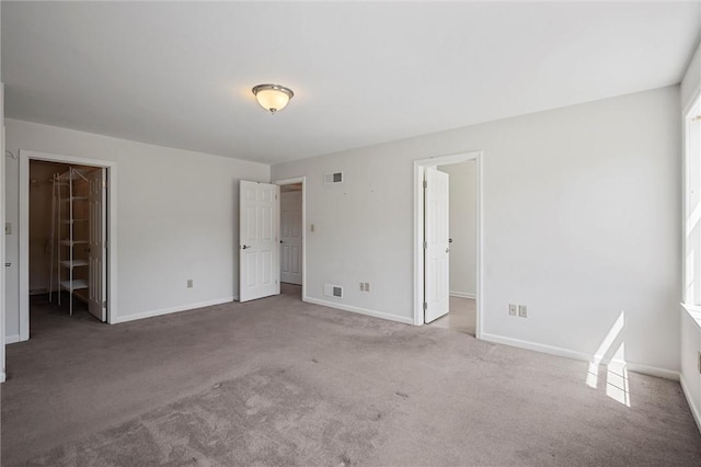 unfurnished bedroom featuring visible vents, carpet, baseboards, and a spacious closet