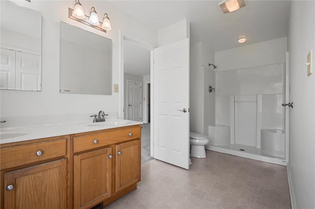 full bathroom with double vanity, a sink, walk in shower, and toilet