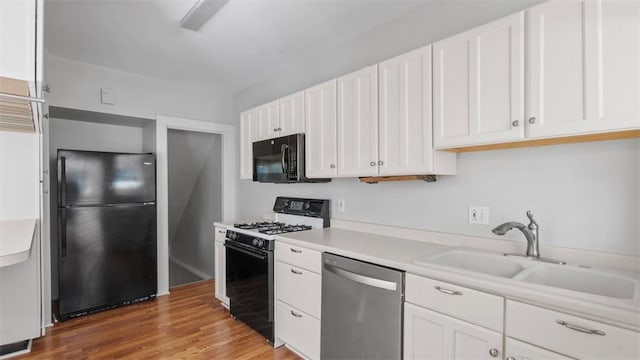 kitchen featuring a sink, white cabinets, and black appliances