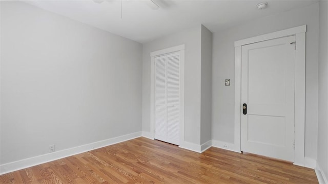 unfurnished bedroom featuring baseboards, a ceiling fan, a closet, and light wood finished floors