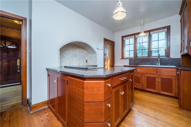 kitchen featuring pendant lighting, dark stone counters, brown cabinets, and light wood finished floors