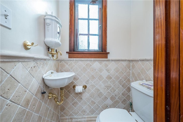 bathroom with wainscoting, a wealth of natural light, toilet, and tile walls