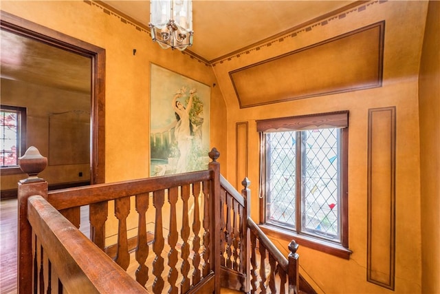 interior space with an inviting chandelier, baseboards, vaulted ceiling, and an upstairs landing