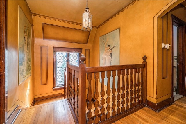 entrance foyer with crown molding, arched walkways, baseboards, wood-type flooring, and a chandelier