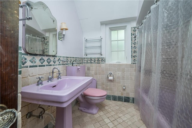 full bathroom featuring toilet, tile patterned floors, tile walls, and a wainscoted wall