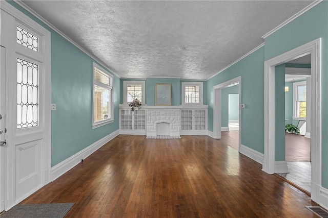 entrance foyer featuring crown molding, baseboards, a fireplace with flush hearth, visible vents, and hardwood / wood-style flooring