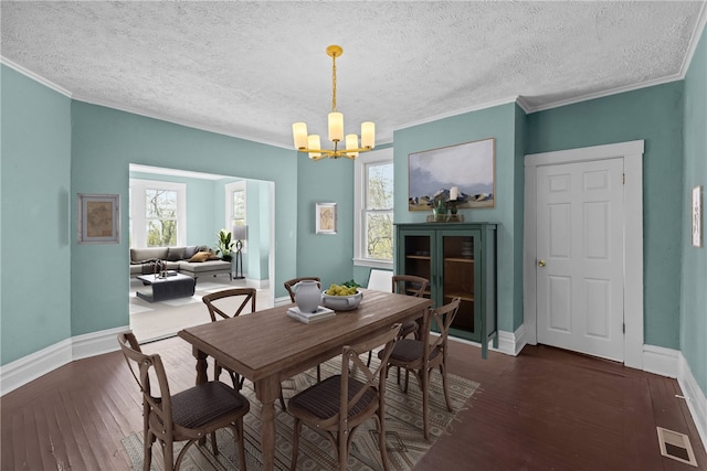 dining area featuring visible vents, ornamental molding, baseboards, hardwood / wood-style flooring, and a notable chandelier