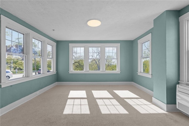 unfurnished room featuring light colored carpet, a textured ceiling, and baseboards