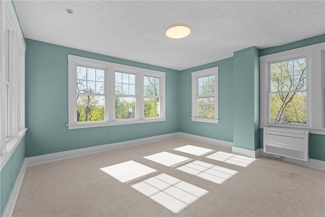 spare room featuring carpet floors, a textured ceiling, and baseboards