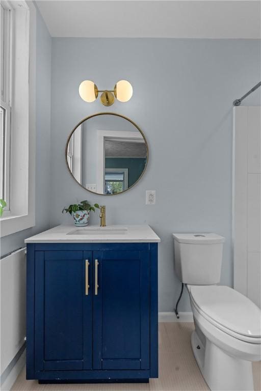 full bath featuring baseboards, vanity, and toilet